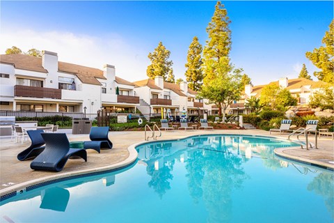 a swimming pool with lounge chairs and buildings in the background